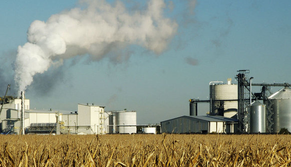 Field of dead corn with ethanol factory pollution in background